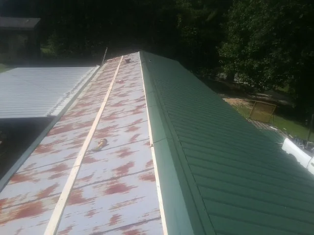 Old rusted panels beside newly installed green metal roofing — Wind Damage Roof Repair by Roofing Brothers in Adamsburg