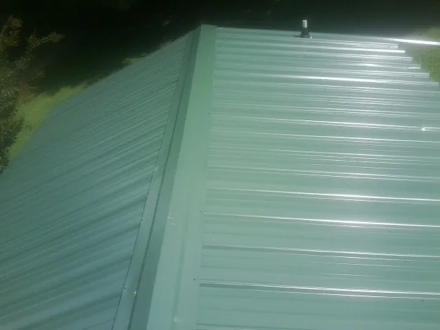 New green metal panels meeting at the ridge of a roof — Flat Roof Repair work by our crew in Adamsburg