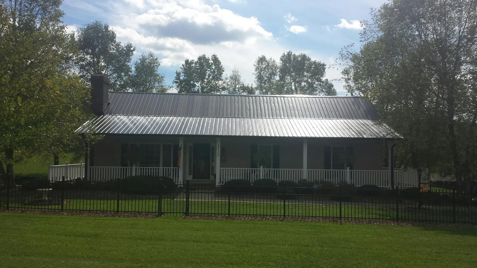 Gray metal roof on a brick ranch with a full width front porch — Gutter Guard Installation work by our crew in Adamsburg