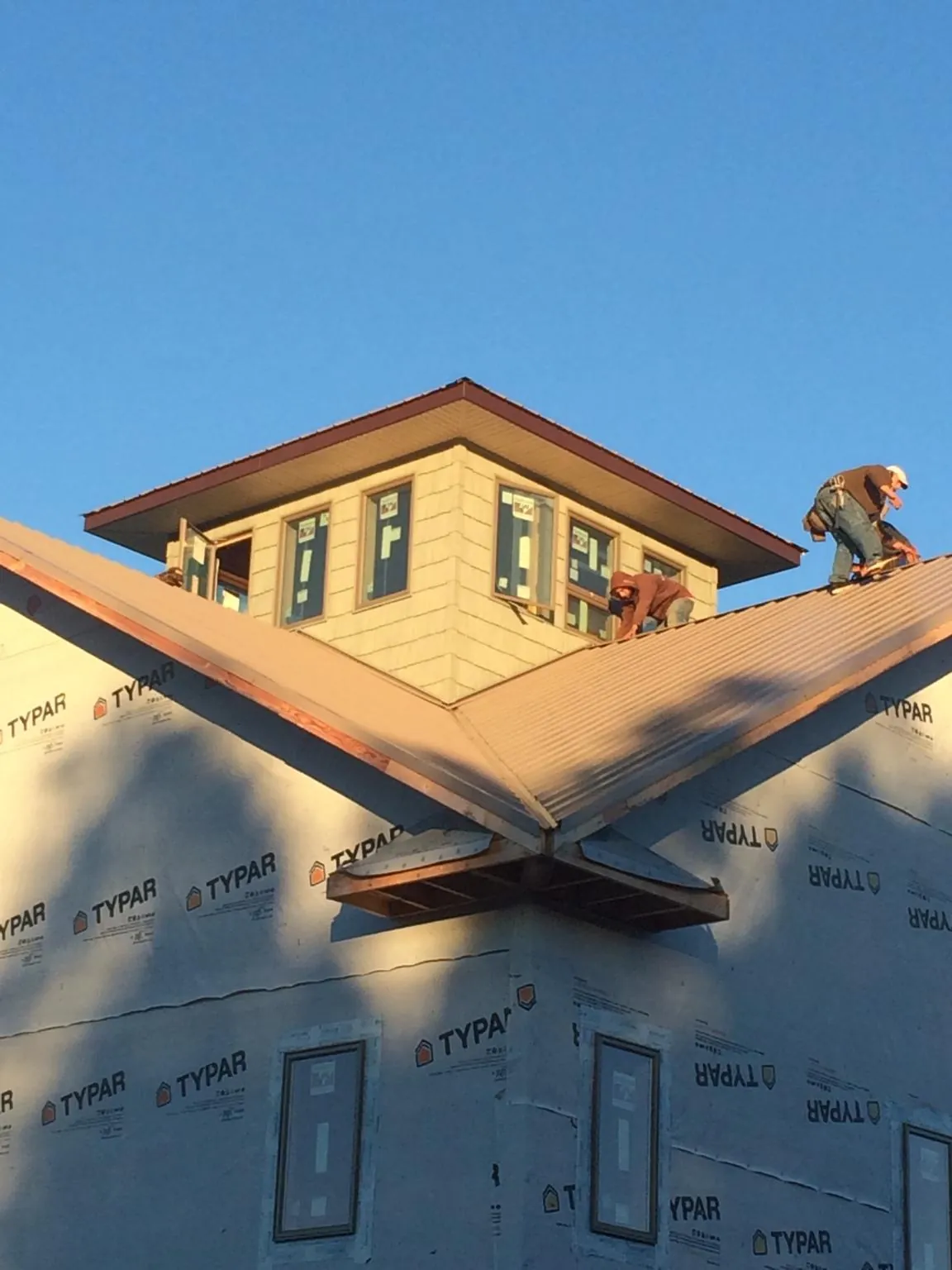 Roofers working around a rooftop cupola on a new metal roof at sunset — Roof Waterproofing in Adamsburg by Roofing Brothers